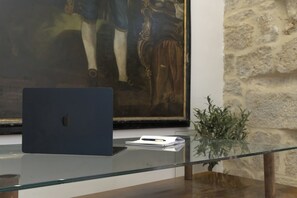 Una computadora portátil sobre una mesa de vidrio, con un cuadro enmarcado al fondo.