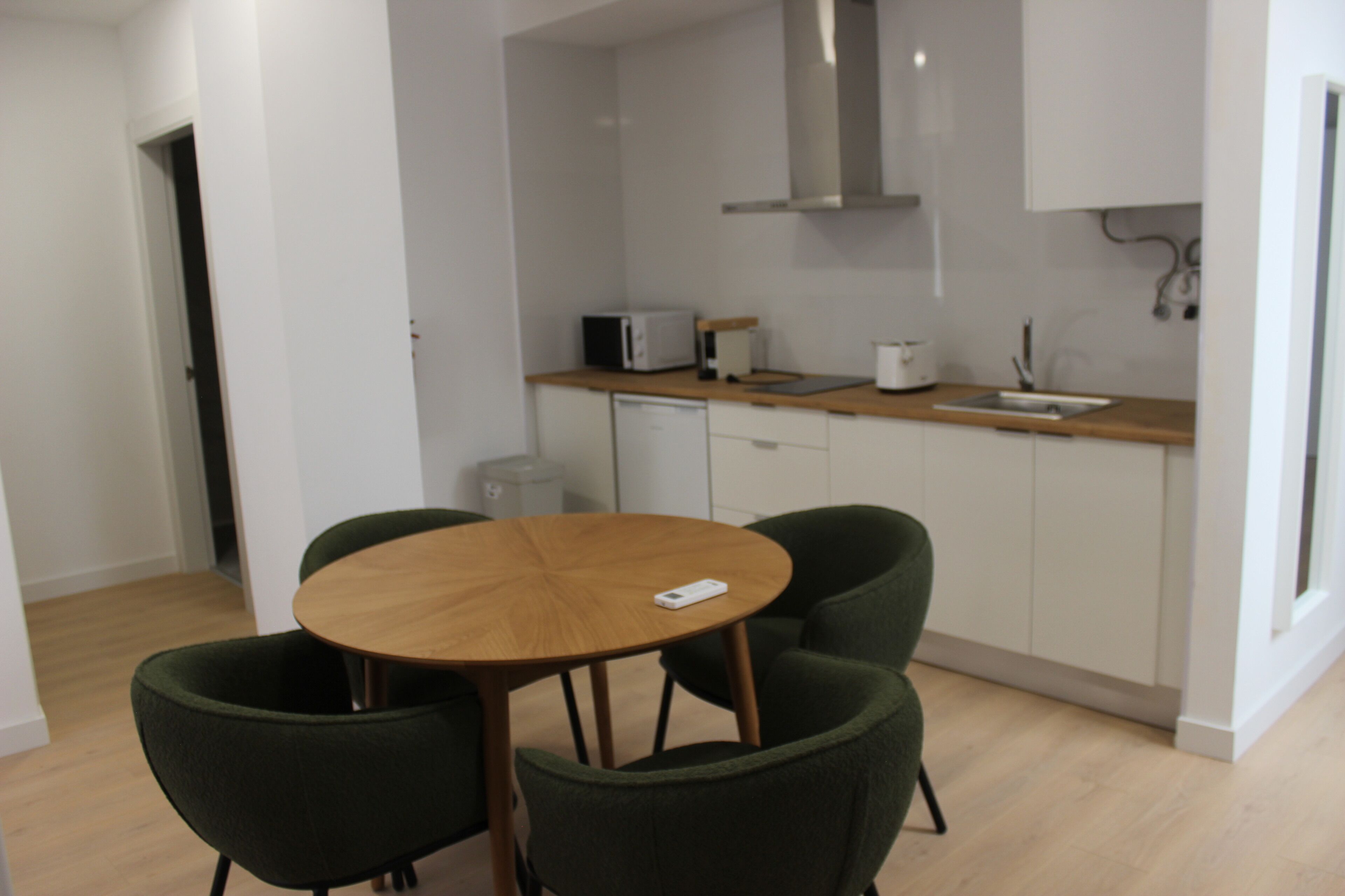 A small kitchen with a round wooden table and two green chairs.