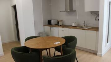 A small kitchen with a round wooden table and two green chairs.