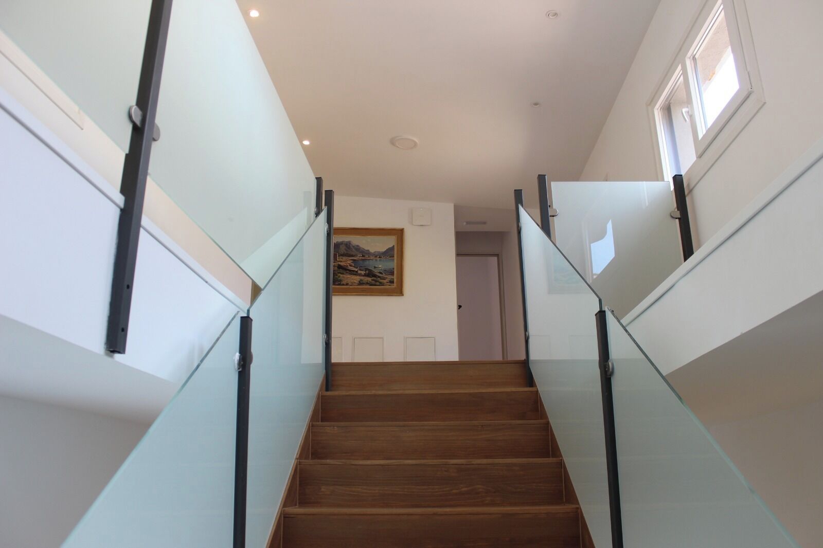 A staircase with glass railings and wooden steps leading to a door.