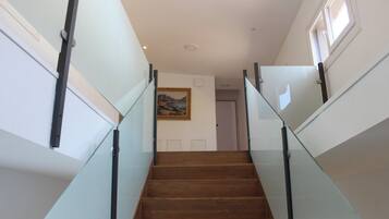 A staircase with glass railings and wooden steps leading to a door.