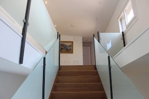 A staircase with glass railings and wooden steps leading to a door.
