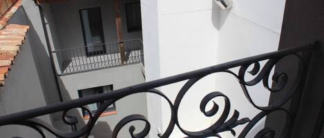 A balcony with a metal railing and a view of a building with a tiled roof.