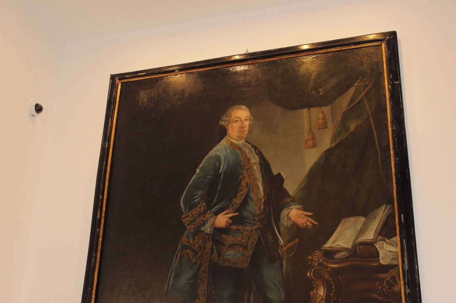 A portrait of a historical figure in a formal setting with a chair and a book.