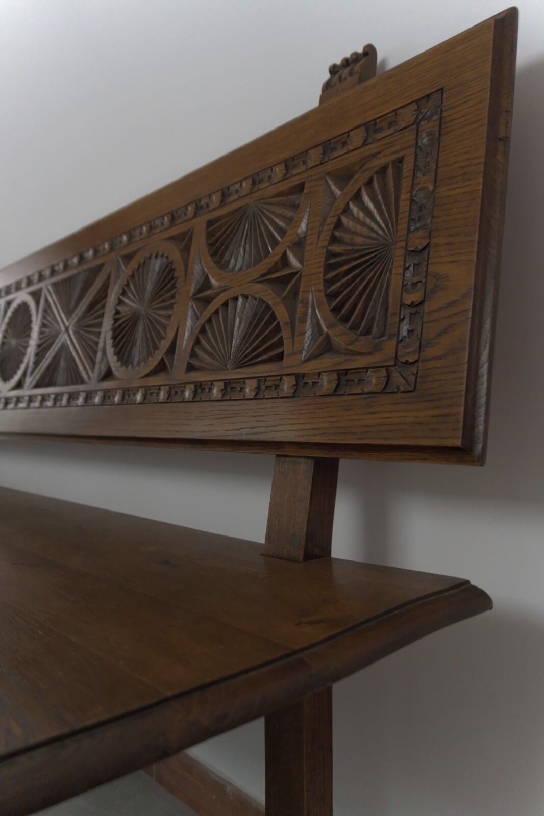A wooden bench with intricate carvings on the backrest.