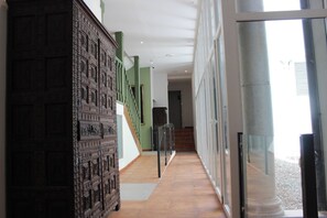 Un pasillo con pared decorada, una escalera y una puerta de vidrio que da al exterior.
