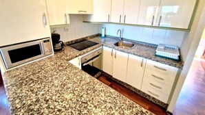 A compact kitchen with white cabinets, a microwave, a sink, and a clock on the wall. - Sunny Palm Villa | Private Pool | Callao Salvaje (Callao Salvaje)