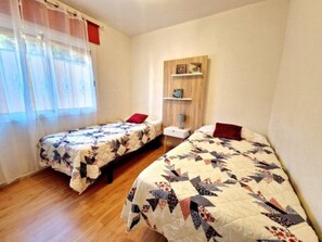 A bedroom with two beds, a wooden shelf unit, and a window with curtains. - Sunny Palm Villa | Private Pool | Callao Salvaje (Callao Salvaje)