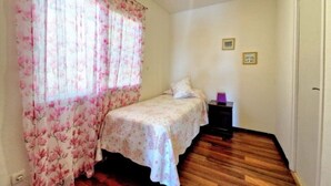 A bedroom with a bed, a nightstand, a window with floral curtains, and a door. - Sunny Palm Villa | Private Pool | Callao Salvaje (Callao Salvaje)