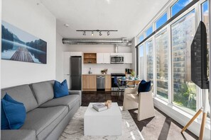 Un appartement moderne comprenant un salon, une kitchenette et de grandes fenêtres.