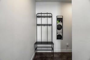 Ein Waschbereich mit einem Metallgestell sowie einer an der Wand befestigten Waschmaschine und einem Trockner.
