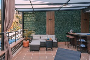 Ein Balkon mit einer Sitzecke, einem kleinen Tisch und einer Bar.