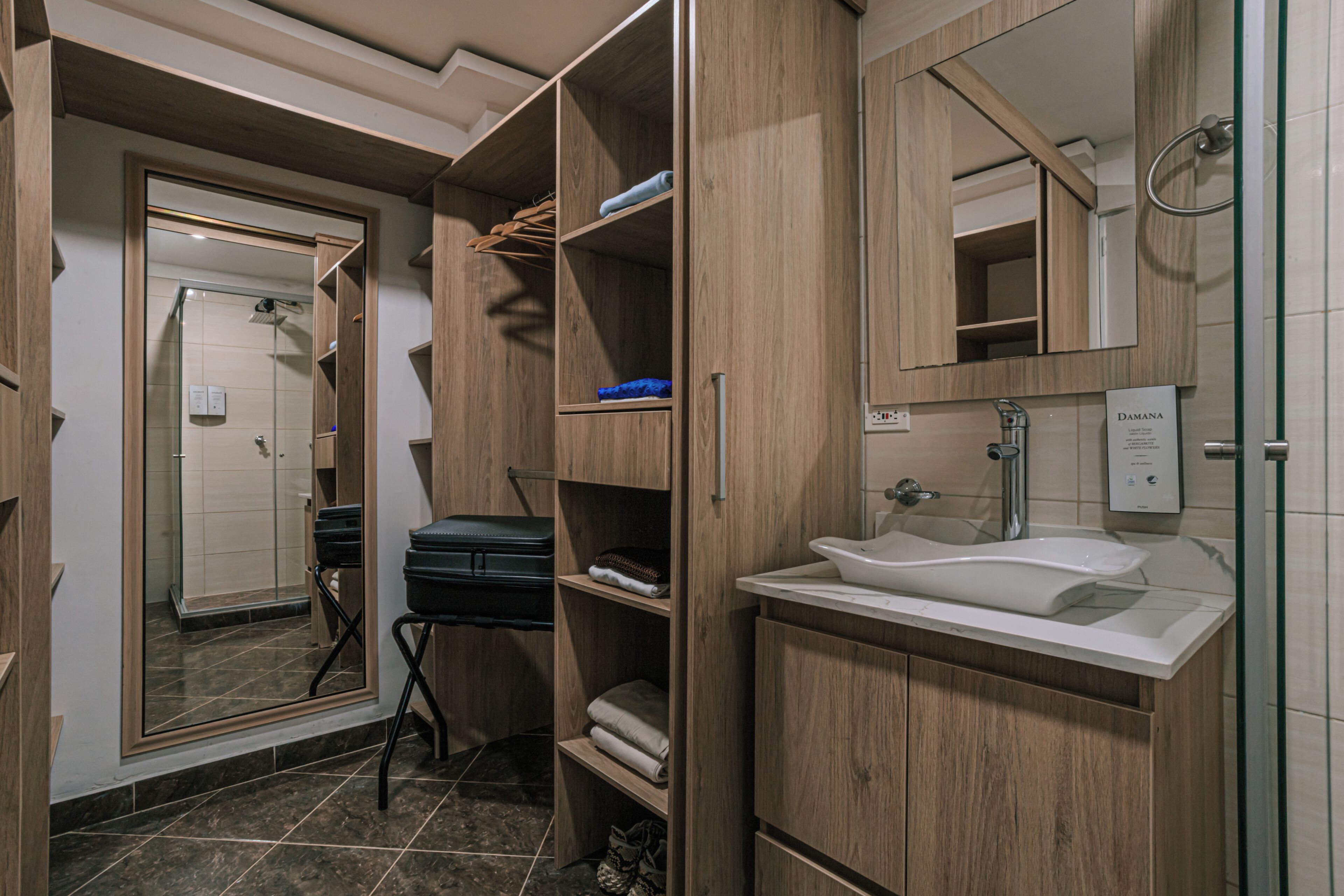 A modern bathroom with a built-in sink, a mirror, and wooden shelving.