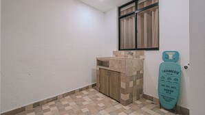 A small bathroom with a sink, a wooden cabinet, and a window with curtains. - Private Jacuzzi, Rooftop & BBQ Loft in Medellín (Medellín)