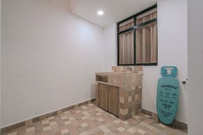 A small bathroom with a sink, a wooden cabinet, and a window with curtains. - Private Jacuzzi, Rooftop & BBQ Loft in Medellín (Medellín)