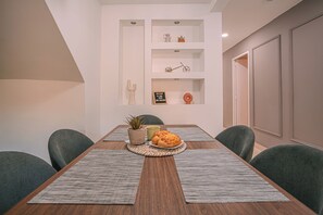 Un coin repas avec une table en bois, des sets de table gris, une plante en pot et une assiette de nourriture.