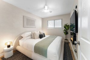 A bedroom with a bed, a ceiling fan, a window with blinds, a potted plant, and a wall-mounted TV. - Fabulous 1-bedroom apartment with AC in vibrant Houston (Houston)