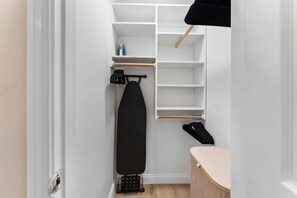 A narrow walk-in closet with white shelving, a hanging rack, and a wooden ironing board. - Fabulous 1-bedroom apartment with AC in vibrant Houston (Houston)