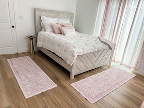 A bedroom with a bed, two rugs, a bedside table, and a window with curtains. - Old Town Scottsdale Getaway! Heated Pool + Hot Tub -4BR (Scottsdale)