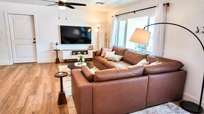 A modern living room with a brown leather sofa, a flat-screen TV, a floor lamp, and a small side table. -  Resort-Style Oasis Near Old Town Scottsdale (Scottsdale)