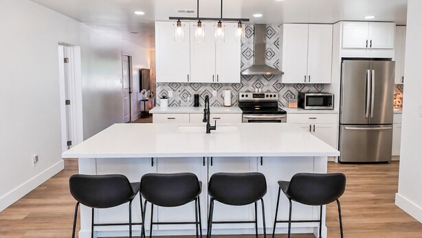 A modern kitchen with white cabinetry, a central island with bar stools, stainless steel appliances, and pendant lighting. -  Resort-Style Oasis Near Old Town Scottsdale (Scottsdale)