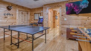 Et værelse med et ping-pong bord, et bordfodboldbord og en spillemaskine.