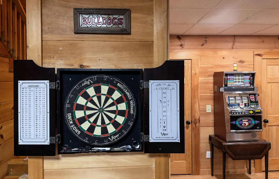 A dartboard with a score chart, a jukebox, and a sign reading 'BULLDOGS'.