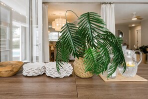 A room with a wooden table, a woven basket, a potted plant, stacked white coasters, a wooden bowl, and a clear glass pitcher. - Designer Pool Oasis | Theater | Golf | Luxury (Palm Beach Gardens)