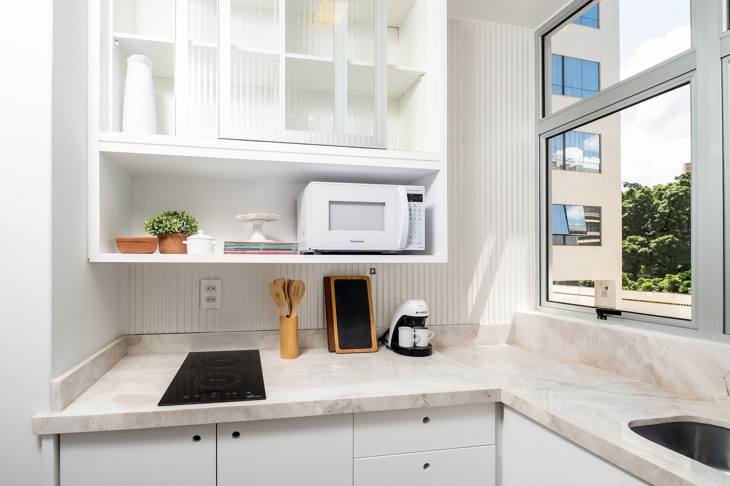 A modern kitchen with a built-in microwave, coffee maker, and a chalkboard.