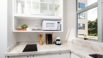 A modern kitchen with a built-in microwave, coffee maker, and a chalkboard.