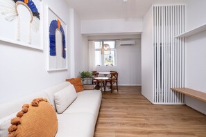 A modern living room with a white sofa, a wooden dining table, and a white partition with vertical slats. - Modern Apartment in the Center of Floripa Vlr301 (Florianópolis)