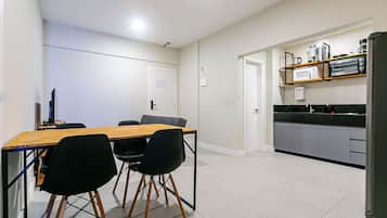 A modern kitchen with a wooden dining table, black chairs, and a built-in microwave.