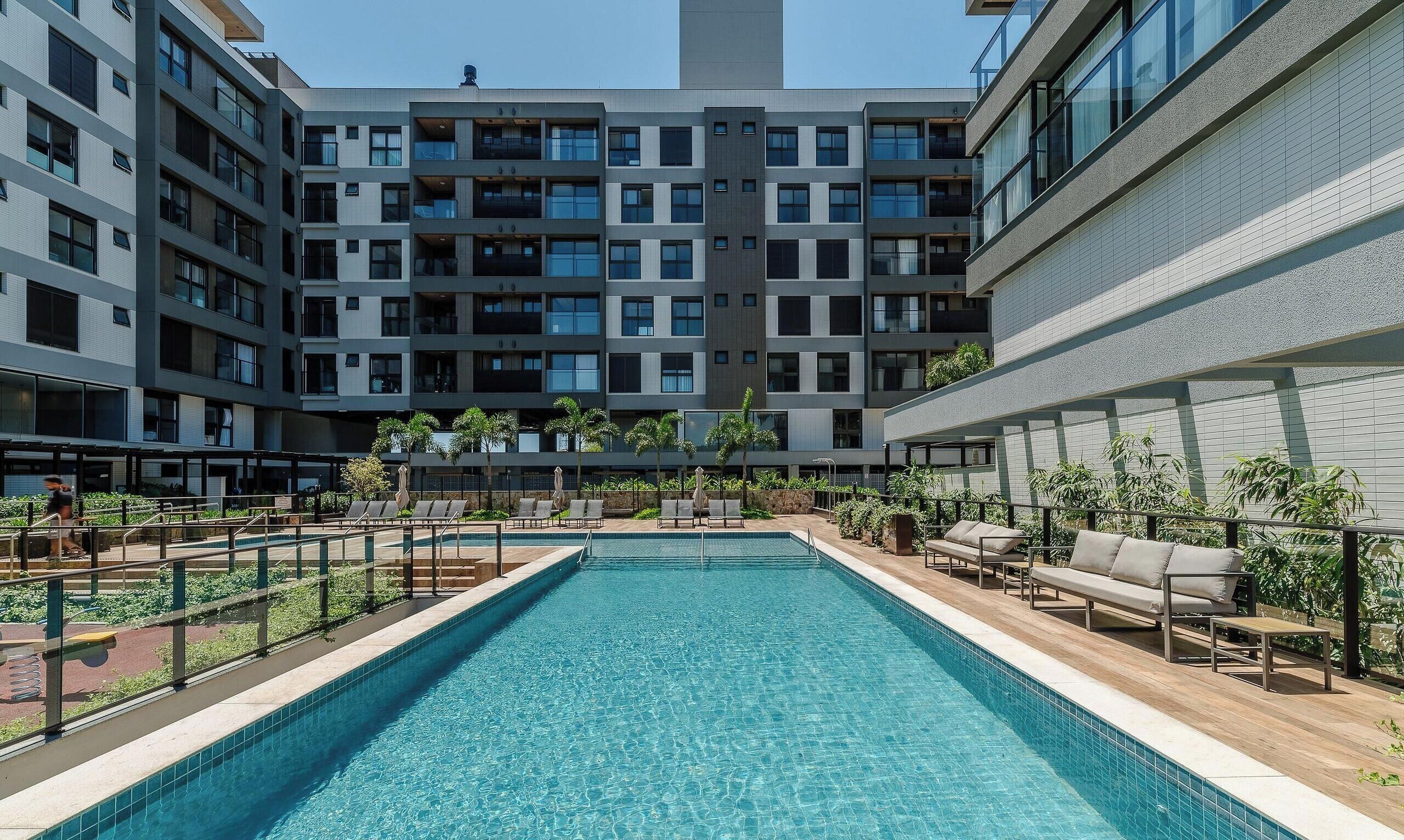 A swimming pool with lounge chairs and a view of a modern apartment building.