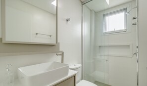 A modern bathroom with a large white sink, a glass shower enclosure, and a toilet. - Modern Lake View Apartment in Jurere Vlo0414 (Florianópolis)