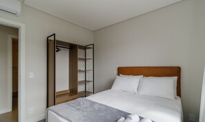 A bedroom with a bed, a wooden wardrobe, and a white headboard. - Modern Lake View Apartment in Jurere Vlo0414 (Florianópolis)