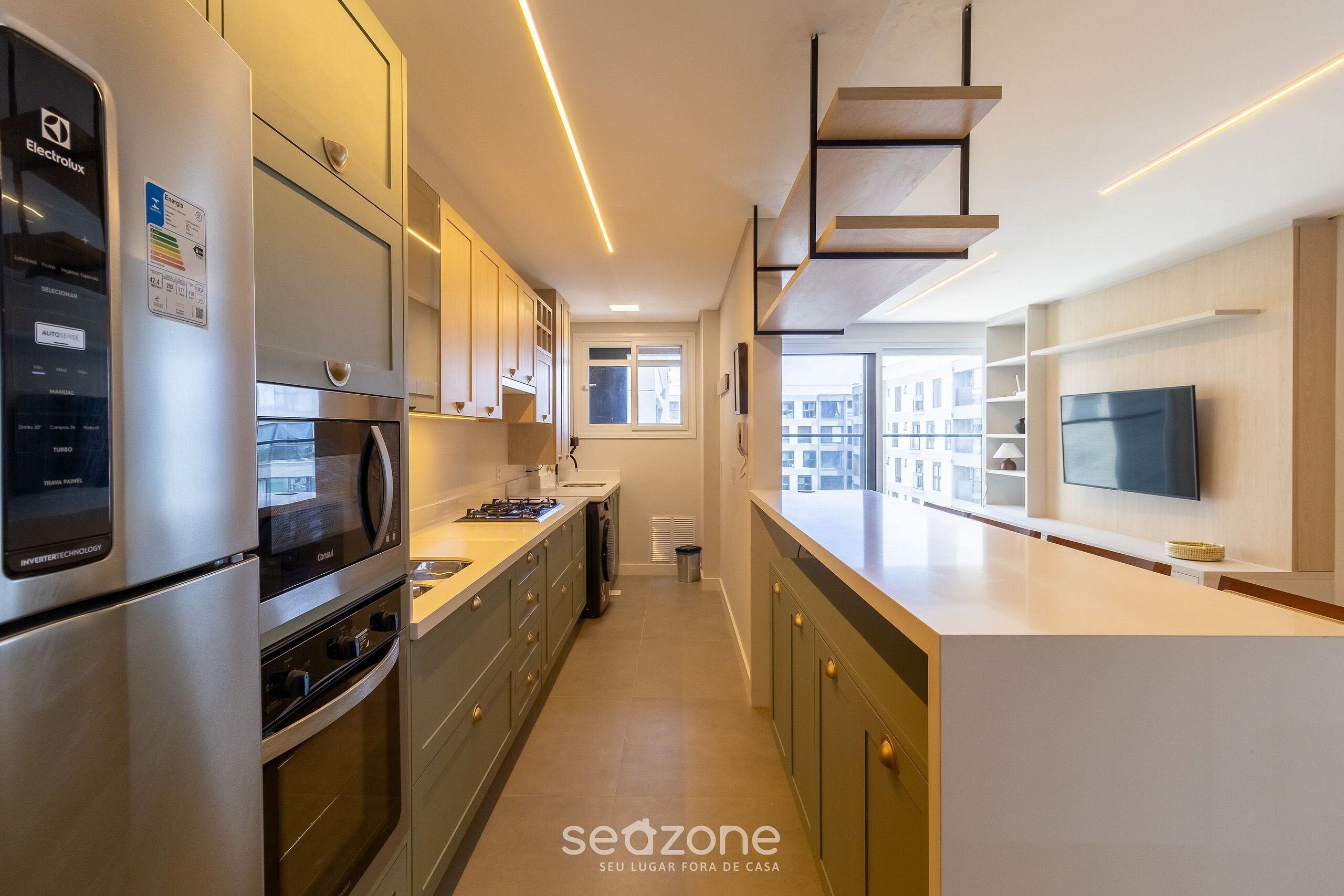 A modern kitchen with stainless steel appliances, a built-in oven, and a microwave. There is a window providing natural light and a view of the city.