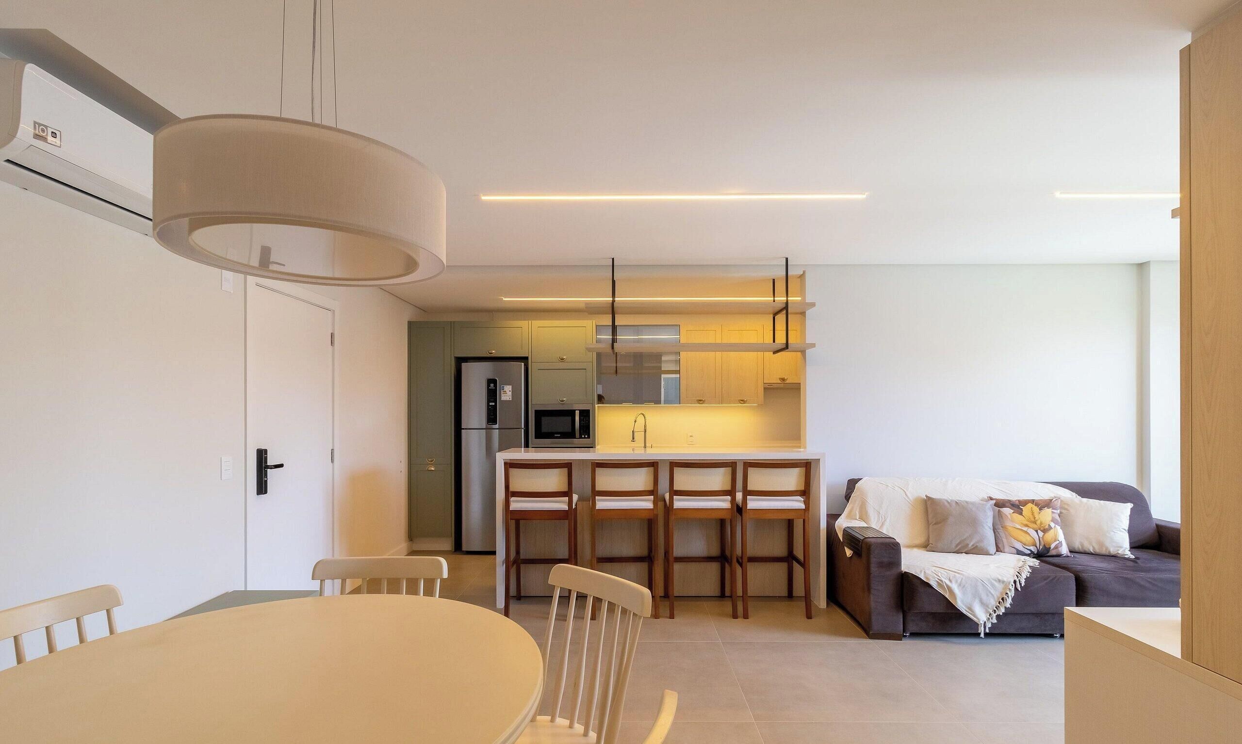 Una cocina moderna con una isla central, un comedor con sillas y una sala de estar con sofá.