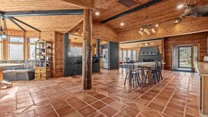 A spacious interior with a high ceiling, wooden beams, a fireplace, and a dining area. - Salt Creek Ranch Lodge - Ranch Escape (Collbran)