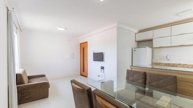 Una cocina moderna con una mesa de comedor de vidrio, un sofá y un televisor montado en la pared.