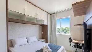 Una habitación de hotel con cama, escritorio, silla, televisor y ventana con vistas.