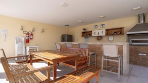 Una cocina con mesa y sillas de madera, refrigerador, horno empotrado y extintor.