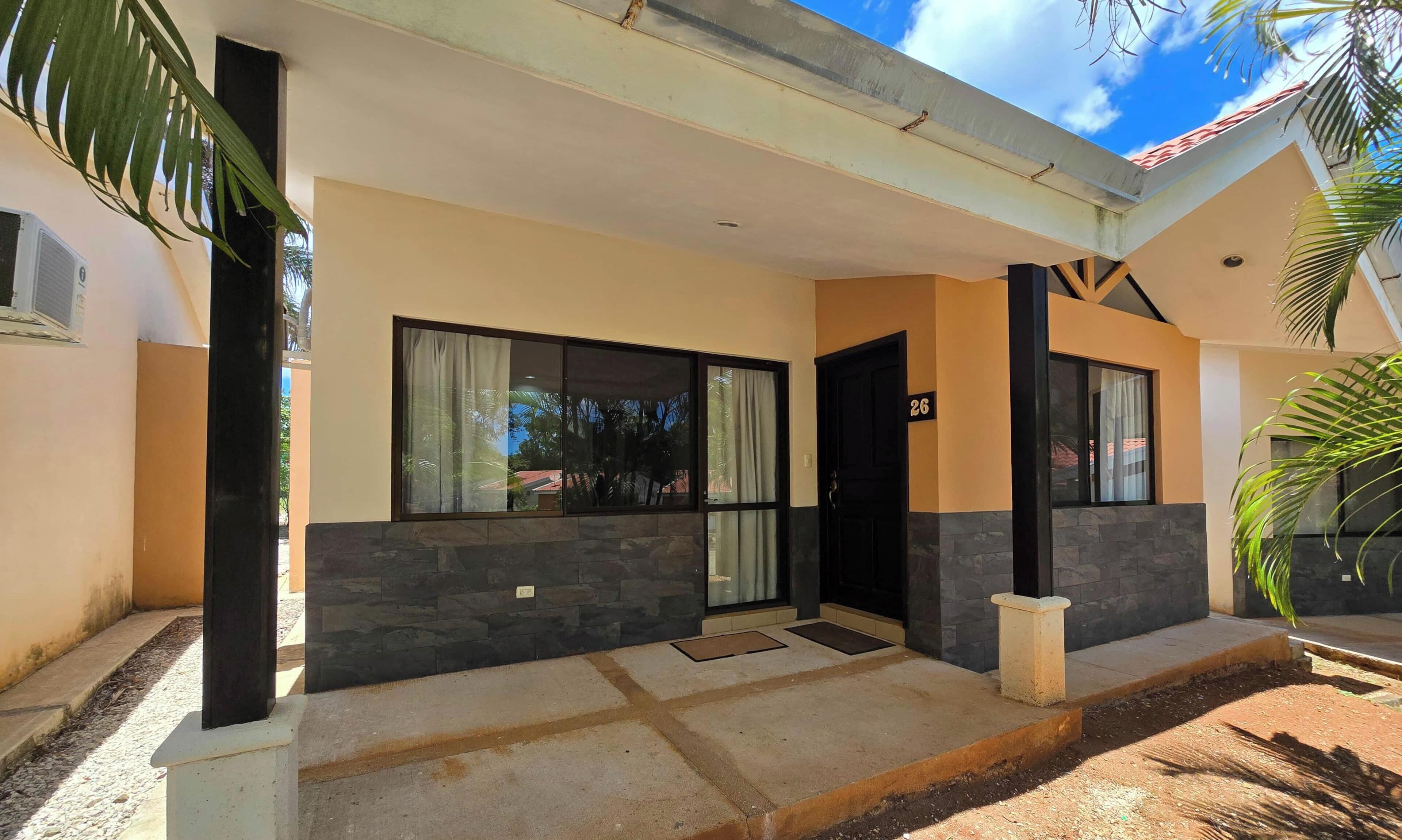 Un edificio moderno con fachada de piedra, ventanas grandes y una puerta con el número 26.