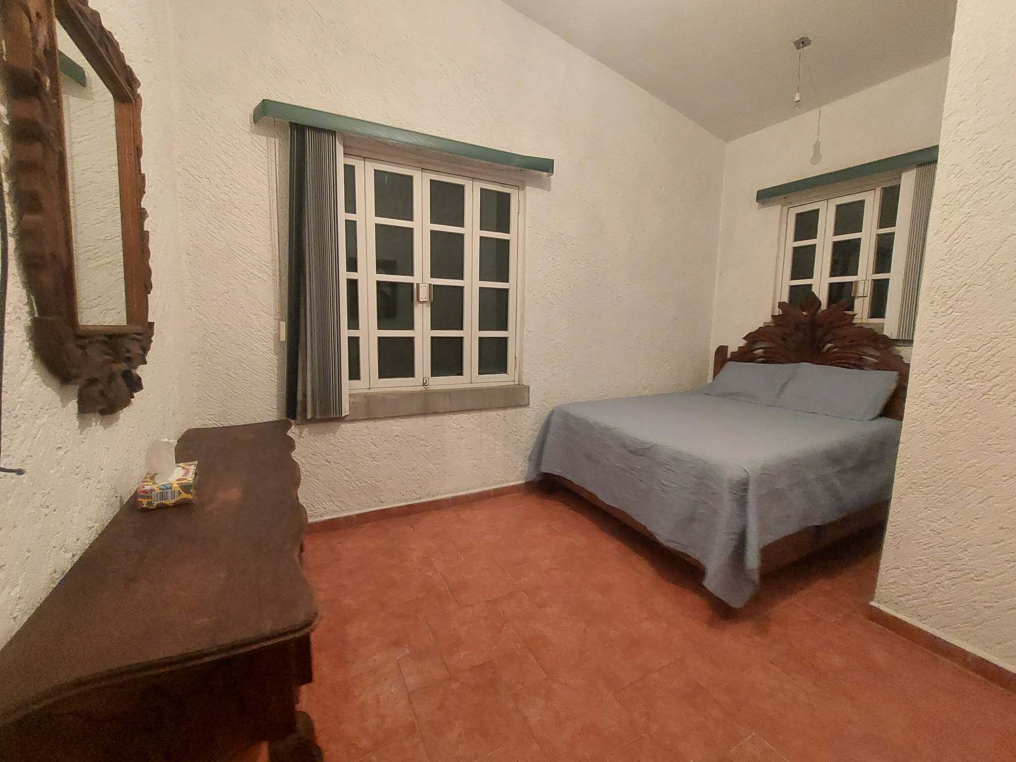 Une chambre à coucher avec un lit, une table de chevet, une fenêtre et un miroir.