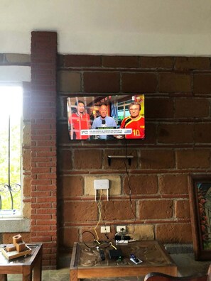 Ein Fernseher an einer Ziegelwand, davor ein Tisch.