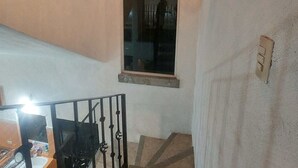 A staircase with a handrail, a window with a decorative frame, and a wall-mounted light fixture. - Tranquil 3-bedroom house in joyas de agua  perfect for relaxing courtesy coffee (Emiliano Zapata)