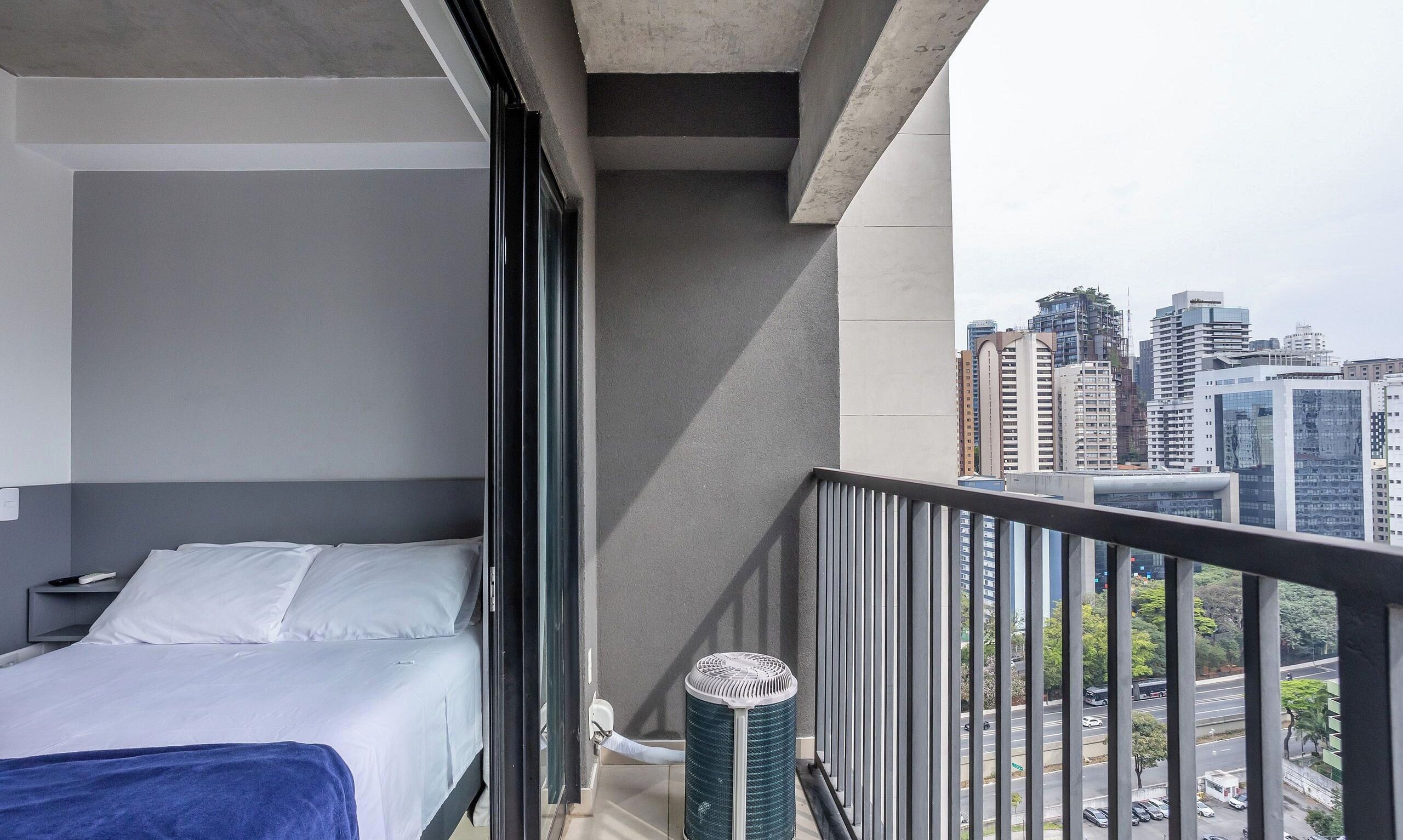 Une chambre d’hôtel moderne avec un lit, une fenêtre et une vue sur le paysage urbain.