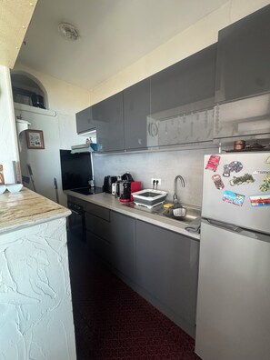A compact kitchen with a refrigerator, microwave, and stove. - Studio facing the sea, Promenade des Anglais (Nice)