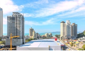 Un edificio de gran altura con una grúa de construcción, un cielo despejado y una vista distante del mar.