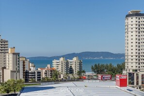 Un edificio alto con varios pisos, vista al mar y cielo despejado.