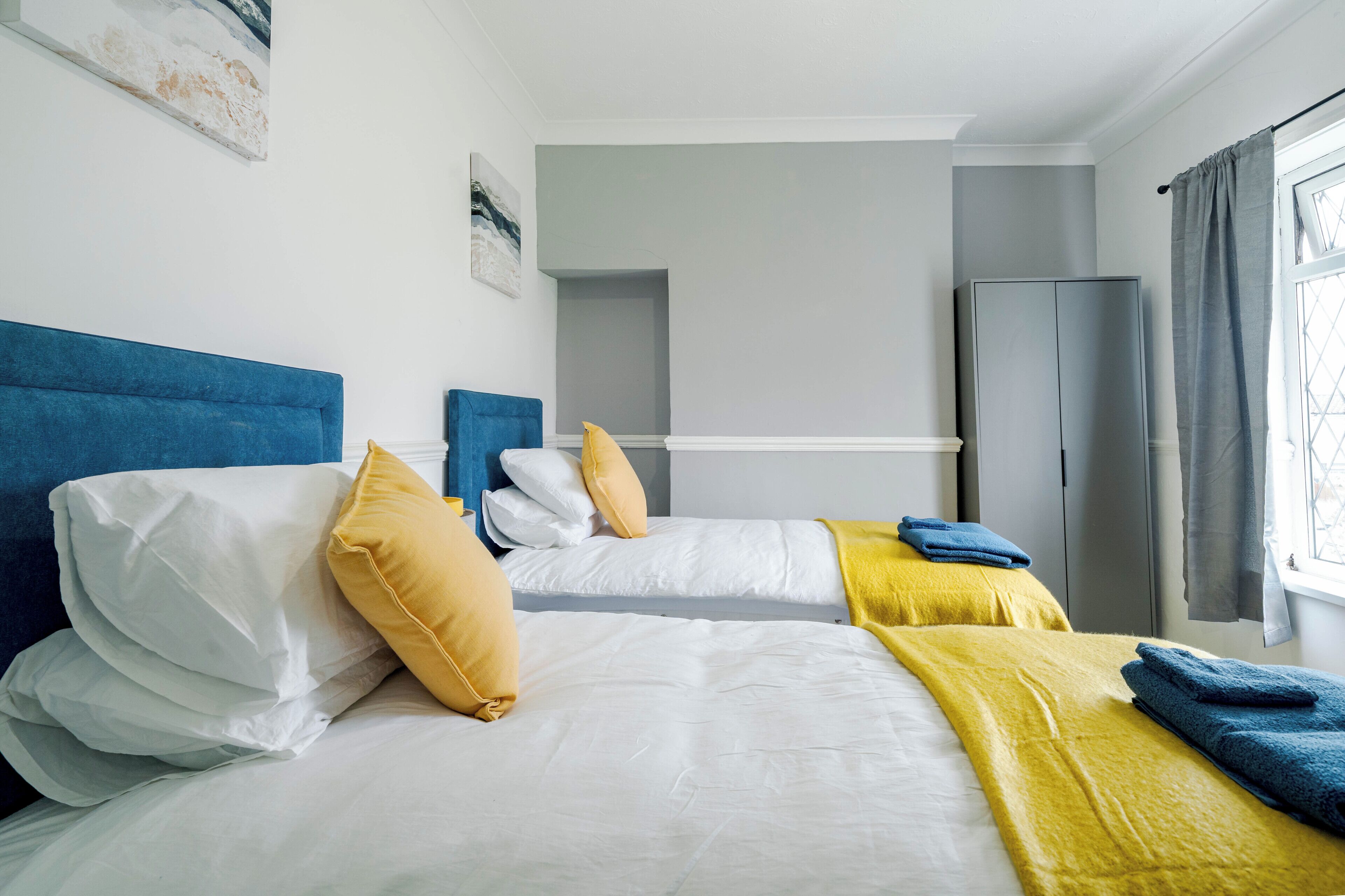 Een hotelkamer met twee bedden, een kledingkast en een raam voorzien van gordijnen.